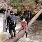 Carol Masheter making a seated crossing of a log bridge